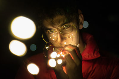 Portrait of man holding illuminated lights