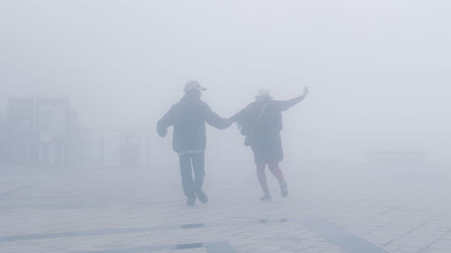 Rear view of people walking on road against sky