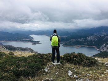 Rear view of man standing on mountain against sky