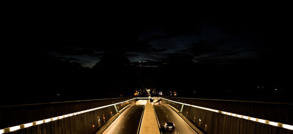 Footbridge over road in city at night
