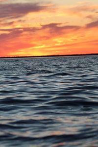 Scenic view of sea against dramatic sky during sunset