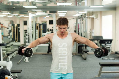 Young man lifting dumbbells in gym