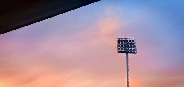 Low angle view of floodlight against sky during sunset