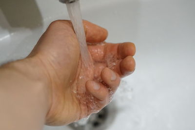 Cropped image of person hand in bathroom