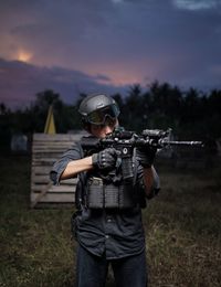 Rear view of man standing on field with gun 