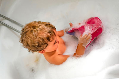 Child bathing in tub at home with foam