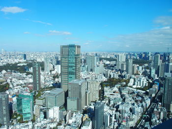 High angle view of modern buildings in city against blue sky