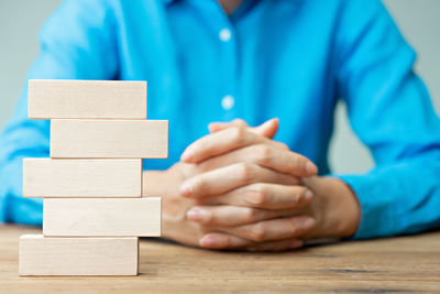 Midsection of man holding blue stack on table