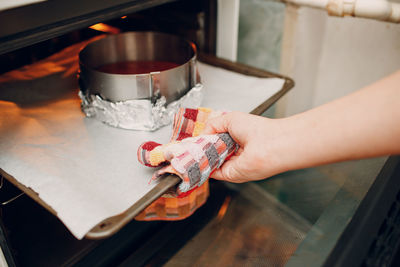 Woman keeping cake container in oven