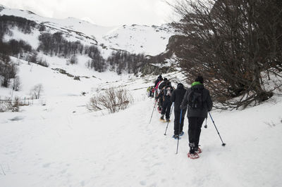 Rear view of people walking on snow covered mountain