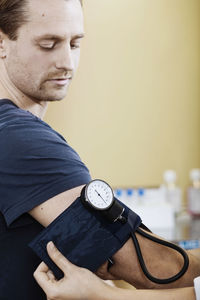 Doctor putting blood pressure cuff on male patient's arm in clinic