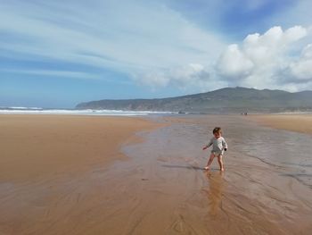 Boy is playing on the beach against sky