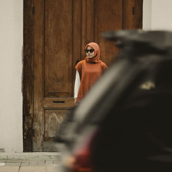 Woman standing near old wooden door