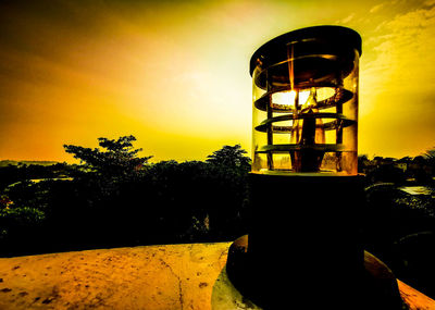 Silhouette water tower against sky during sunset