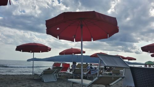 Deck chairs and parasols on beach against sky