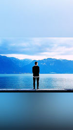 Rear view of man looking at sea against sky