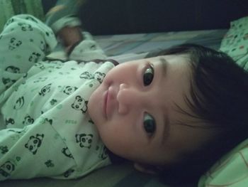 Portrait of cute baby lying on bed at home