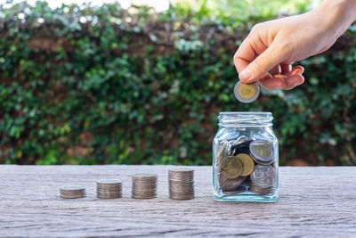 Close-up of hand holding jar against white background