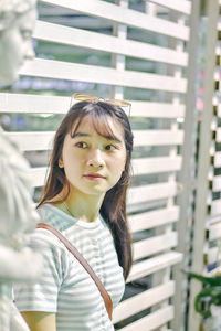 Young woman standing by sculpture against window outdoors