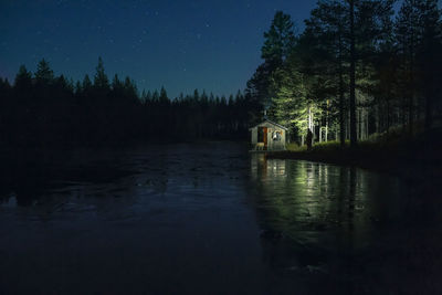 Small wooden cabin at lakeshore at night