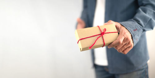 Midsection of man holding paper while standing against white background