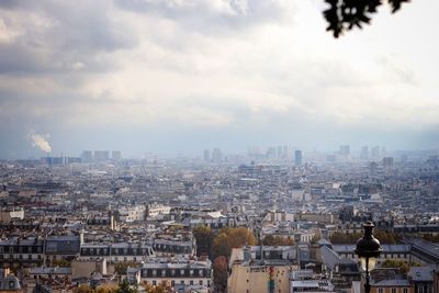 High angle view of parisian buildings against cloudy sky