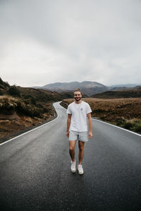 Full length portrait of smiling man standing on road