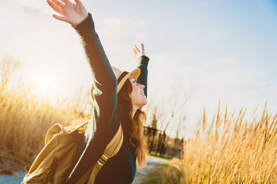 Woman with arms raised on field against sky