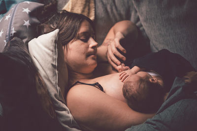 High angle view of mother breastfeeding son while lying on bed at home