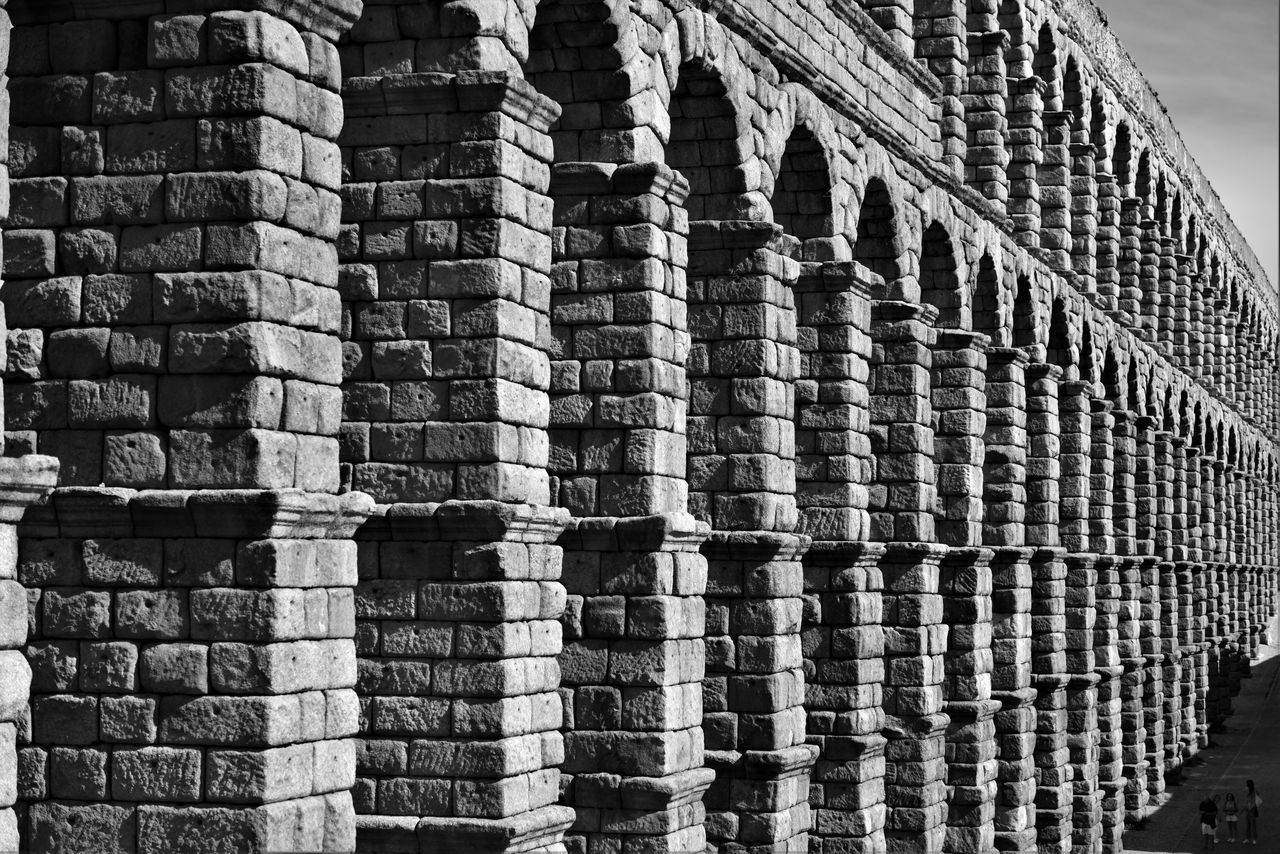 architecture, black and white, built structure, monochrome, monochrome photography, building exterior, no people, wall, day, building, black, brick, pattern, outdoors, iron, in a row, nature, history, repetition, line, the past, city, wall - building feature, sunlight