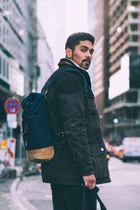 Side view portrait of young man standing on street in city