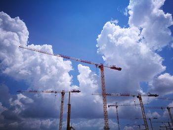 Low angle view of cranes at construction site against sky