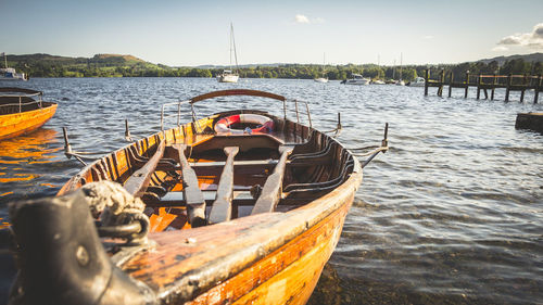 Rowboats moored on river against sky