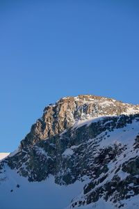 Low angle view of snowcapped mountain against blue sky