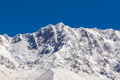 Scenic view of snowcapped mountains against clear blue sky