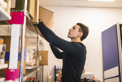 Male store owner removing box from shelf while working