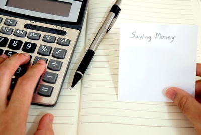 Cropped hands with message and calculator on book