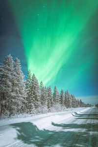 Scenic view of snow covered land against sky during aurora borealis