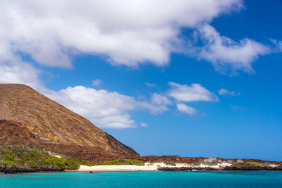 Scenic view of hill by sea at santiago island against sky