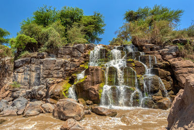 Scenic view of waterfall against sky