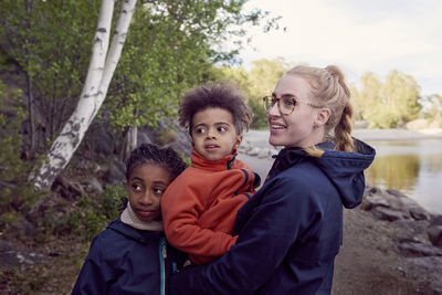 Smiling mother with children standing at campsite