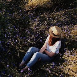 High angle view of woman wearing hat while sitting on grassy field