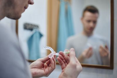 Young man preparing silicon tray for teeth whitening and bleaching gel syringe. 