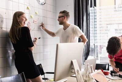 Young business people discussing on adhesive notes in new office