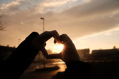 Silhouette person holding hands against sky during sunset