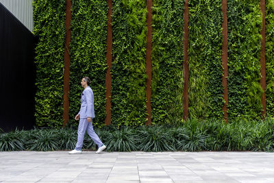 Mature businessman walking on footpath by hedge