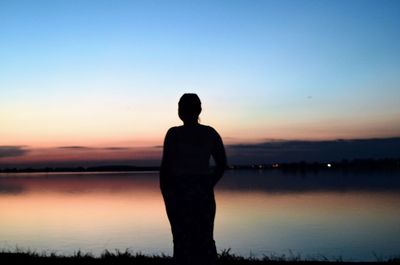 Silhouette man looking at sea against sky during sunset