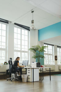 Businesswoman working at computer desk in creative workspace