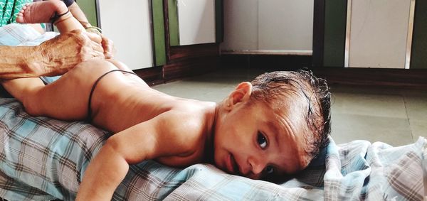 Midsection of woman massaging naked baby boy at home