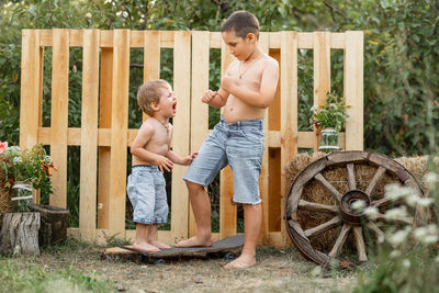 Full length of shirtless boy standing in yard